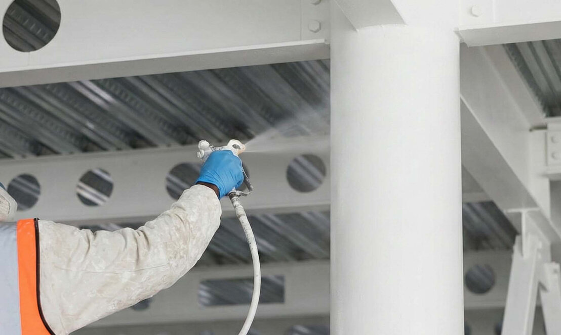 Technician spraying intumescent coating on site